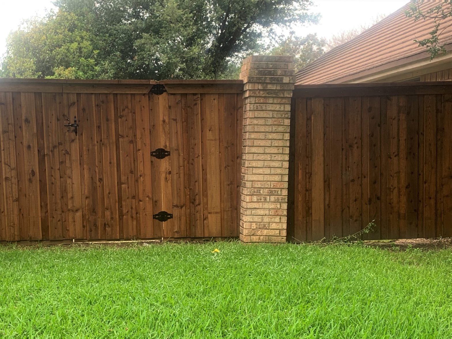 Photo of a stained wood fence with brick pillars